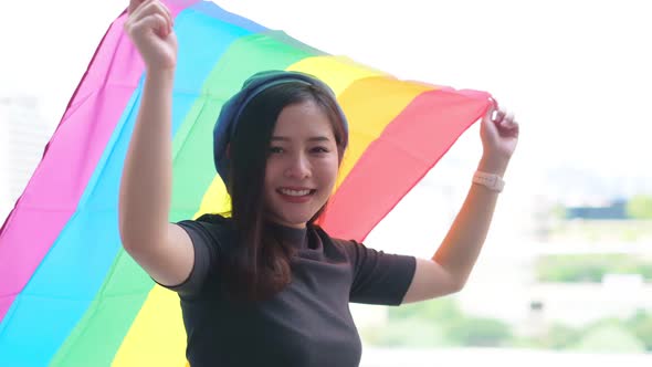 Happy loving homosexual lesbian LGBT couple with rainbow flag at city
