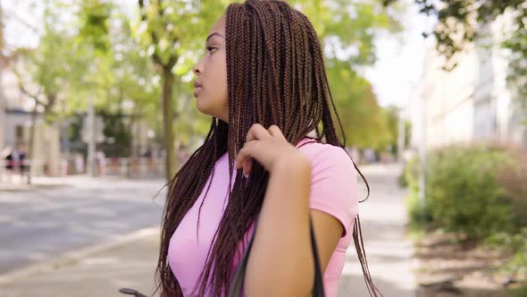 A Young Black Woman Puts on a Face Mask in the Street in an Urban Area - Closeup