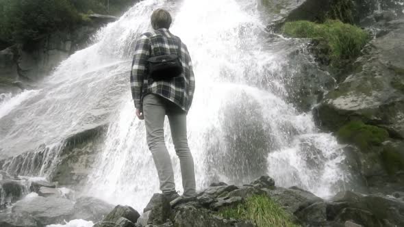 Man standing in front of a beautiful waterfall in Norway, Europe at day time, Slow motion, 120fps