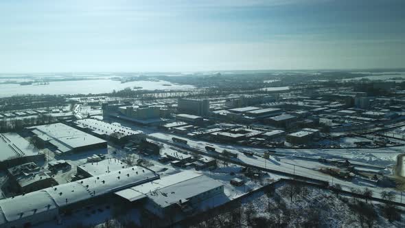 Factory buildings covered with snow. Railway. In the backlight of the setting sun.