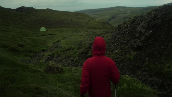 dramatic iceland landscape, person hiking on trail to the tent, camera following movmement, camera t