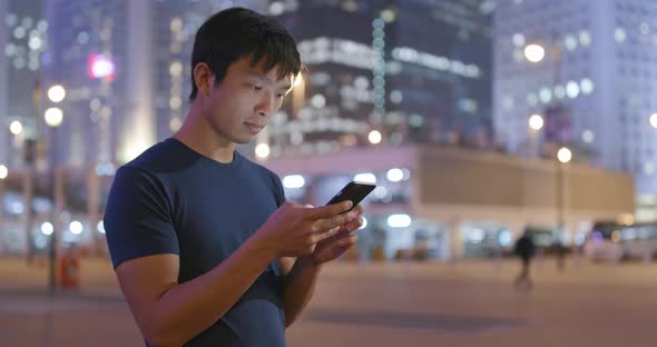 Asian man use of mobile phone in city in the evening