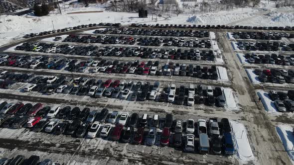Aerial view over large snowy parking lot on a sunny day. A few open spaces.