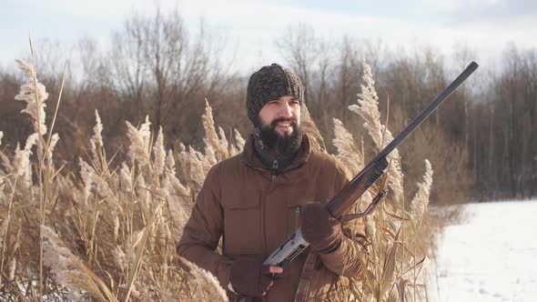 Happy Cheerful Hunter Holding a Rifle and Looking Aside