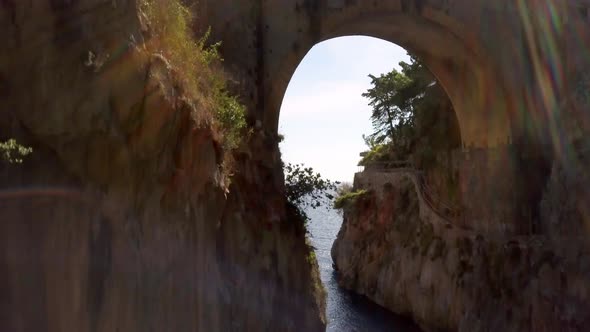 Fiordo di Furore arch bridge with car traffic passing above and boats on the ocean, Amalfi coast in