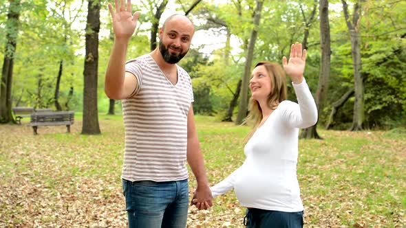 Handsome Man and Young Happy Pregnant Woman Smile To Camera and Wave with Hands