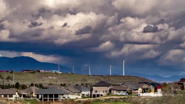 Time Lapse of wind turbines turning on a beautiful cloudy day in a suburban setting with a river and