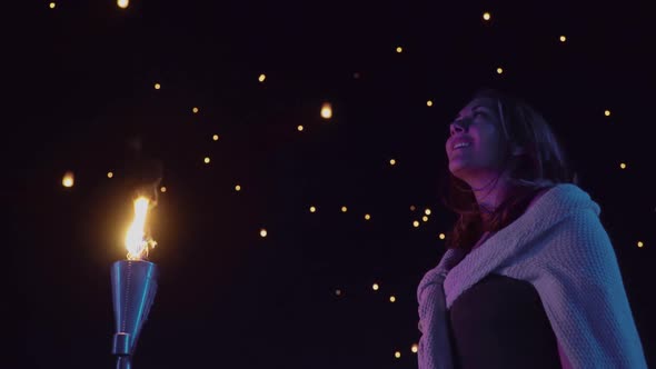 Woman watches as sky lanterns fly Into the night sky