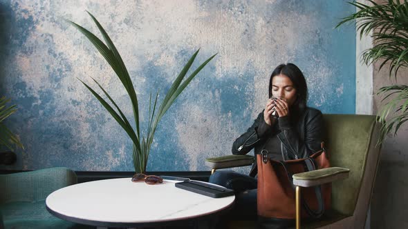 Young Stylish Woman Drinking Coffee in Cafe