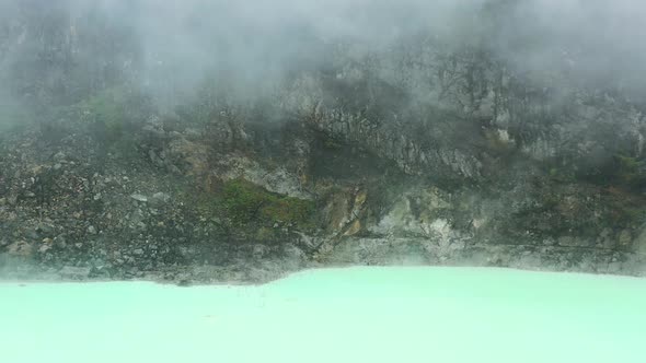 rocky mountain landscape at crater rim of Kawah Putih with neon water shoreline