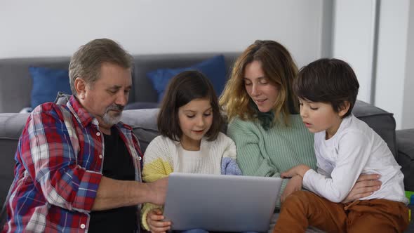 Grandfather with Two Grandchildren and Daughter Making Video Call Using Laptop