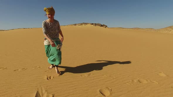 Happy woman dancing barefoot in desert, Egypt