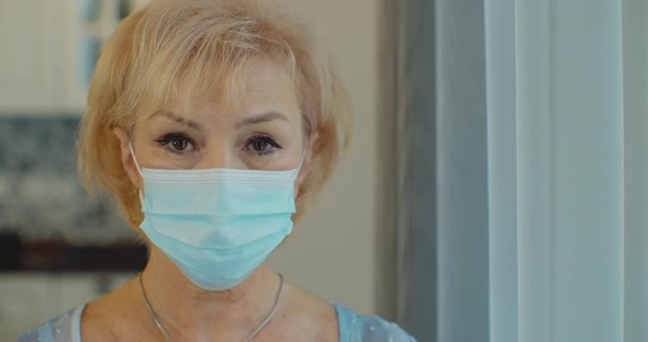 An Elderly Woman in a Protective Mask at Home