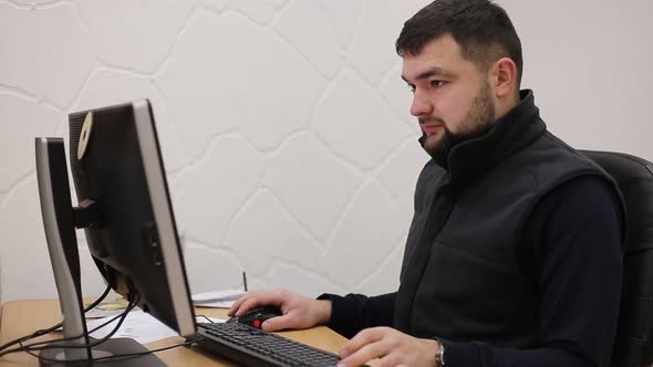 Young bearded office worker man working behind desk on computer
