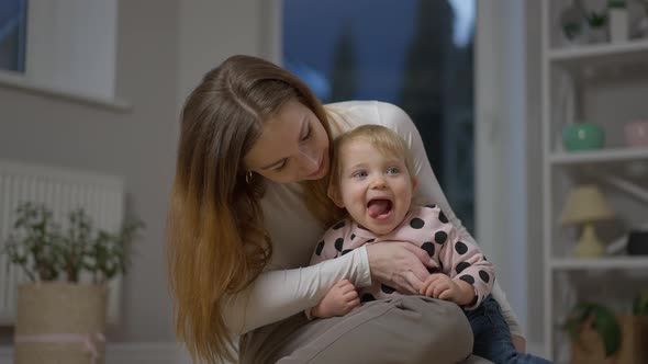 Charming Baby Daughter and Mother Showing Tongues Looking at Camera