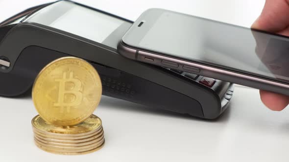 Close Up Man Hand Contactless Paying By Smartphone and Bitcoin Coins on the Table