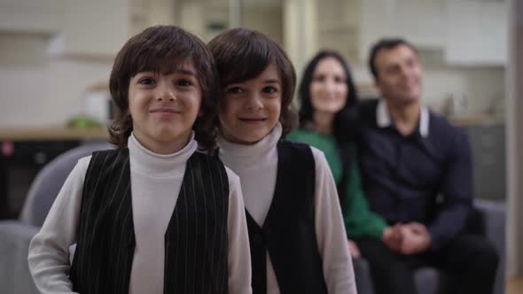 Medium Shot of Charming Middle Eastern Twin Brothers Posing in Living Room with Blurred Couple of