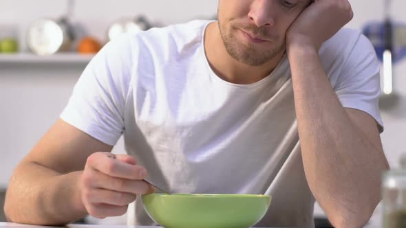 Bored Man Slowly Eating Tasteless Cereal With Milk, Dreams About Tasty Breakfast