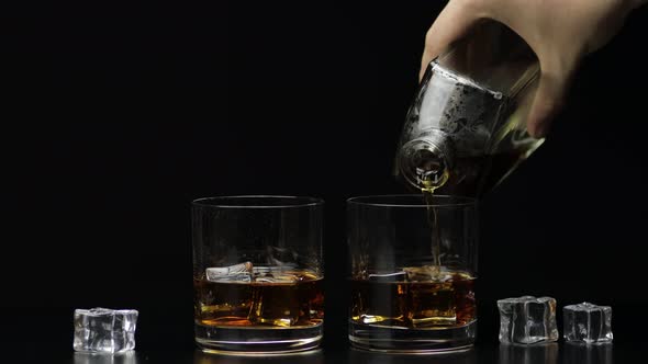 Pouring Whiskey, Cognac Into Glass. Black Background. Pour of Alcohol Drink