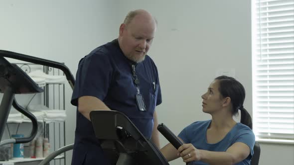 Therapist instructing woman on bicycle machine.