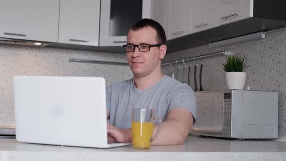 Freelancer Man Finishes Day of Remote Work From Home and Drinks Orange Juice