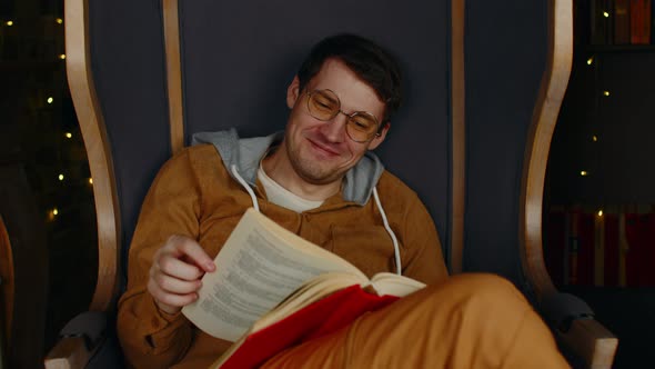 Young man in glasses reading book.