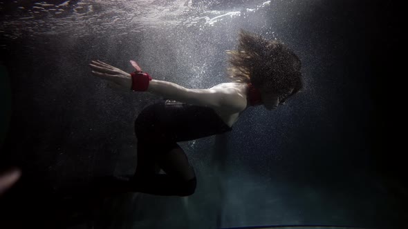 A Woman in a Black Suit Floats Upside Down Under the Water Her Long Hair Flowing