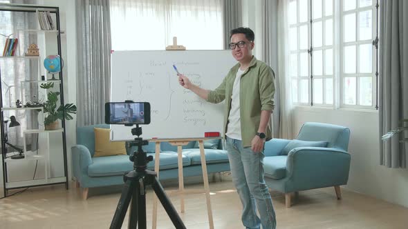 Asian Male Teacher With Glasses Shoots Video By Smartphone Camera While Teaching English At Home