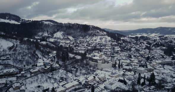 Wide aerial shot of a Mining town Banska Stiavnica in winter covered by snow, twilight