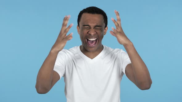 Screaming Frustrated Young African Man, Blue Background