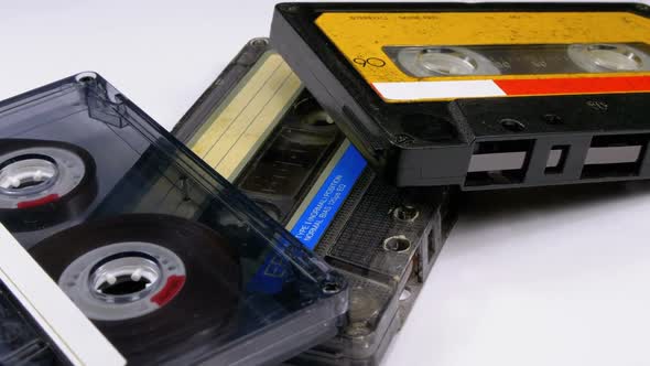 Three Vintage Audio Cassettes Rotate on White Background