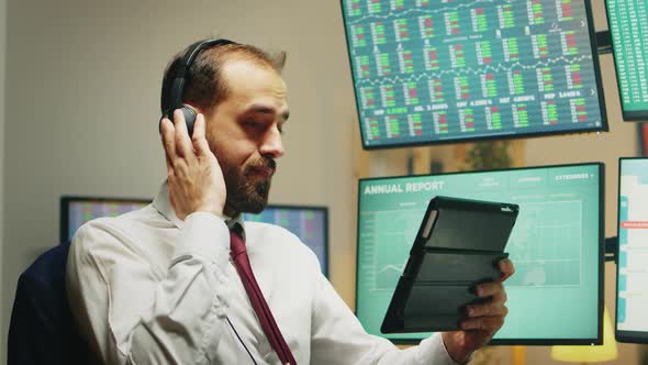 Stock Market Broker Having a Conversation on Headphones While Using Tablet Computer