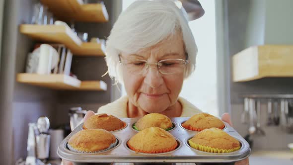 Grandma holding muffin trey and smelling fresh muffins 