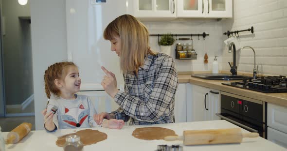 Young Mother and Daughter Having Fun Baking Cookies in the Kitchen Together