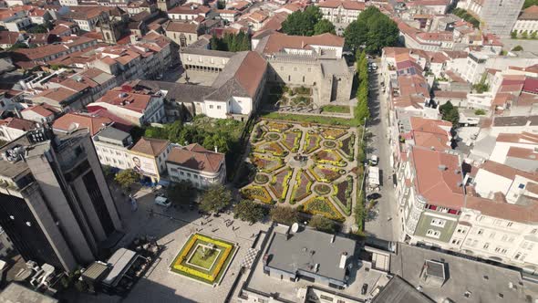 Aerial circular view of Braga city center, with people walking by and flowerbeds.