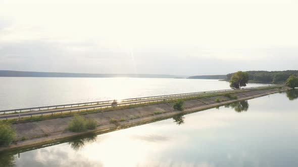 Aerial View to Biker Riding on Motorbike at Dam Route with Sunshine at Background