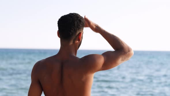 Backside View of Relaxing Young African Man Traveler on the Beach Handsome and Confident Topless Guy