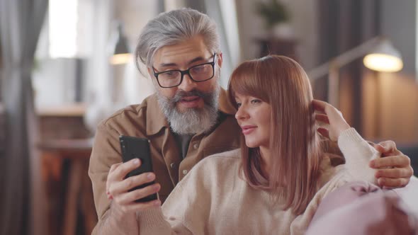 Beautiful Family Couple Using Smartphone and Chatting at Home