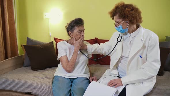 Elderly Caucasian Woman Doctor Listening To Elderly Patient Breathing Medical Exam with Stethoscope