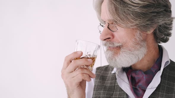 Senior Man in Eyeglasses Looking at Glass of Whiskey