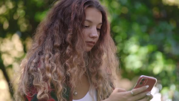 Concentrated Young Woman Types on Cellphone Sitting in Park