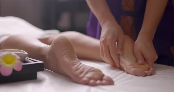 Young and Beautiful Woman Gets Foot Massage Therapy in the Spa Salon