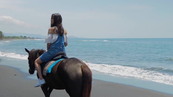 Cute Chinese Teenager Rides a Horse On The Beach In Bali