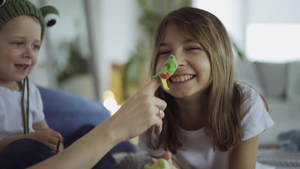 adorable mother and her children, daughter and little son play toys on fingers