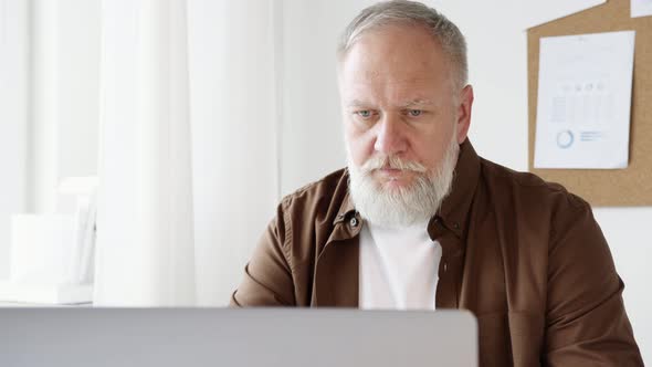 an elderly male businessman working on a laptop