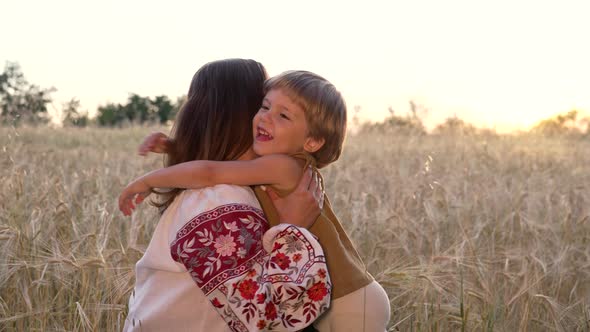 Tender Scene of Loving Son with Mom on Wheat Field Sunset Backdrop