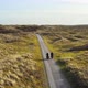 Man and woman riding bikes on dirt road, Nes, Friesland, Netherlands - VideoHive Item for Sale