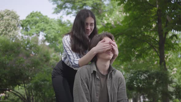 Portrait Handsome Young Man with Braces and Long Hair Sitting in the Foreground, His Girlfriend