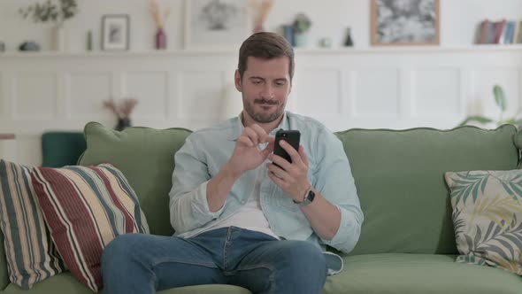 Young Man Having Success on Smartphone at Home