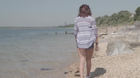 Young Woman Walks Along Beach and Picks Up Plastic Bottle In Slow Motion - Ungraded